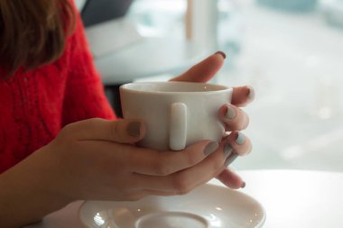 Kız beyaz fincan tabağı üzerinde tutuyor