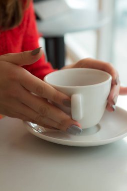 Kız beyaz fincan tabağı üzerinde tutuyor