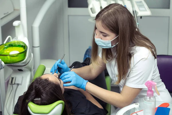 Дантист на работе осматривает женские зубы — стоковое фото