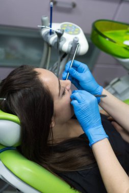 Dişçi kadının diş inceleyerek iş başında