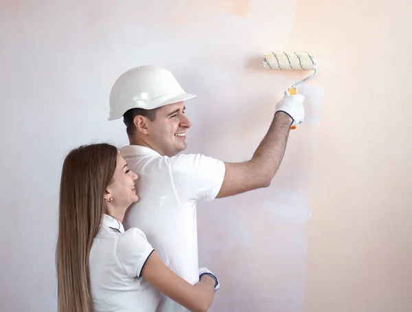Молода пара малює внутрішню стіну нового будинку — стокове фото