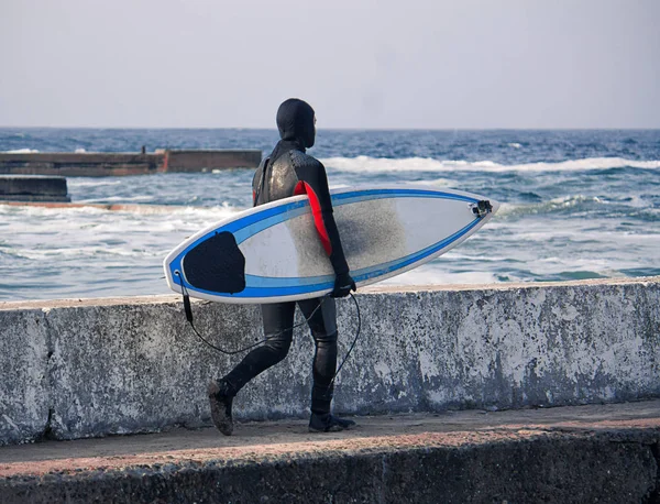 Surfer mit Surfbrett geht auf der Seebrücke ins Wasser — Stockfoto
