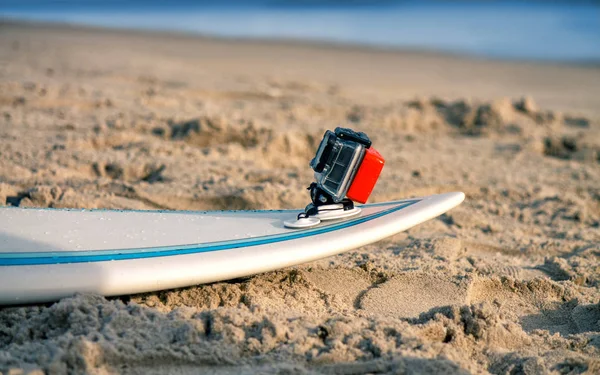 Surfbrett mit aufgesetzter Action-Kamera liegt im Sand — Stockfoto