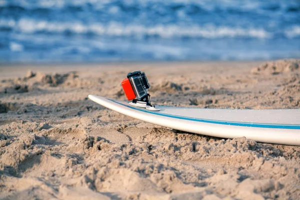 Surfbrett mit aufgesetzter Action-Kamera liegt im Sand — Stockfoto