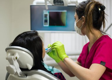 Diş hekimi kadının diş kamerayla incelenmesi