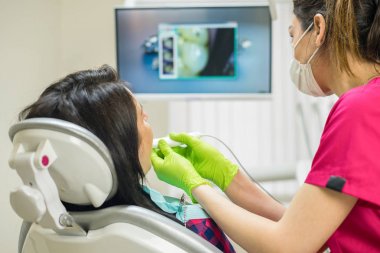 Diş hekimi kadının diş kamerayla incelenmesi