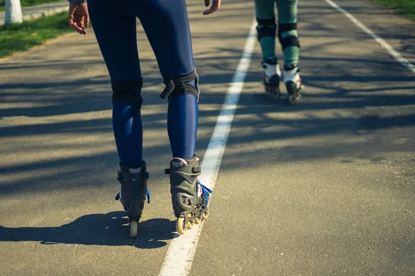 Dos chicas en patines se pasean por la carretera una al lado de la otra —  Fotos de Stock