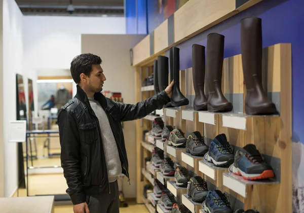 Jovem cliente masculino escolhendo botas de borracha ou gomas watertights — Fotografia de Stock
