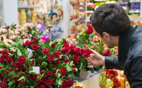 Handsome man choosing roses at a florist shop for his girlfriend