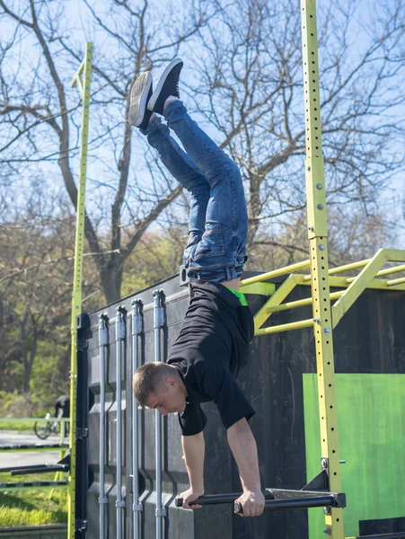 Joven atleta haciendo una parada de mano en barras paralelas en un gimnasio al aire libre —  Fotos de Stock