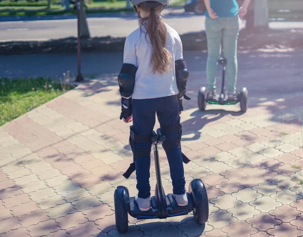 Joven madre e hija montando mini hoverboard eléctrico en el parque — Foto de Stock