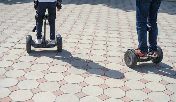 Young father and daughter riding electric mini hoverboard in park