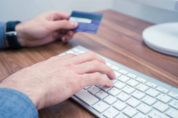 Руки, держащие кредитную карту и печатание на клавиатуре, делая онлайн покупку — стоковое фото