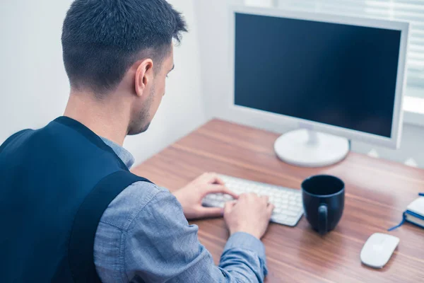 Офисный работник сидит на клавиатуре, глядя на экран — стоковое фото