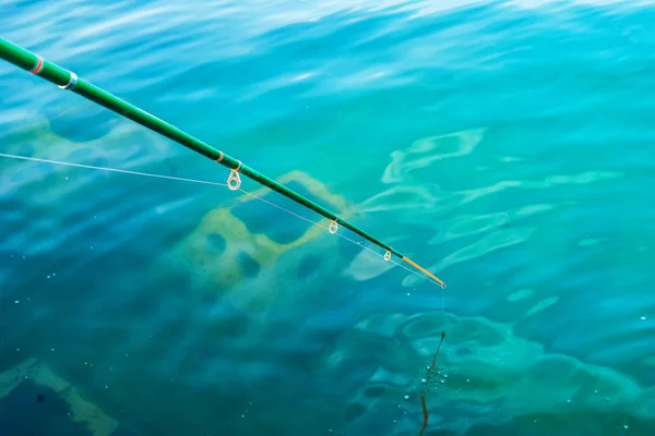 Vara de pesca amador em água azul clara — Fotografia de Stock