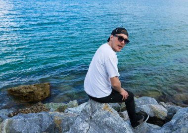 Açık ağızlı merak adam kayanın üzerinde oturuyor