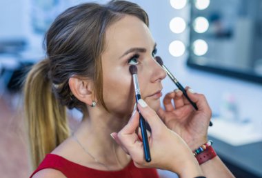 Güzel bir genç kızla dumanlı gözler makyaj yapıyor makyaj sanatçısı