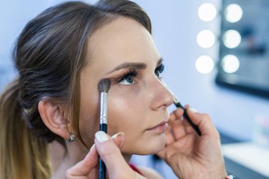 Güzel bir genç kızla dumanlı gözler makyaj yapıyor makyaj sanatçısı