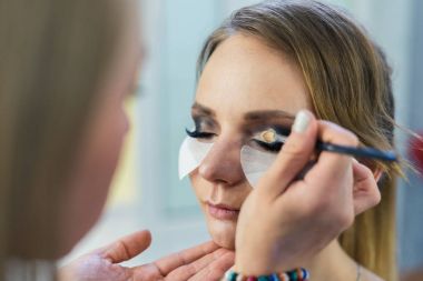 Güzel bir genç kızla dumanlı gözler makyaj yapıyor makyaj sanatçısı