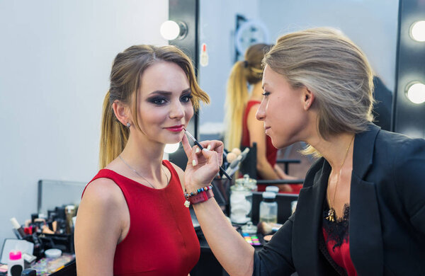 Make-up artist doing smoky eyes makeup to beautiful young girl