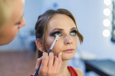 Güzel bir genç kızla dumanlı gözler makyaj yapıyor makyaj sanatçısı