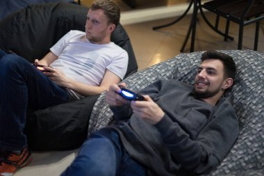 Fasulye çanta sandalyede oturan joystick ile video oyunları oynarken mutlu çift arkadaş
