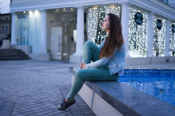 분수 근처에 앉아 밤 도시에 혼자 아름 다운 여자 — 스톡 사진