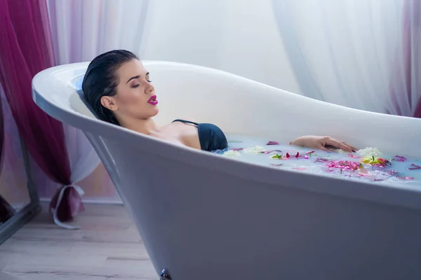 Sexy donna bruna rilassante in un bagno caldo con fiori — Foto Stock