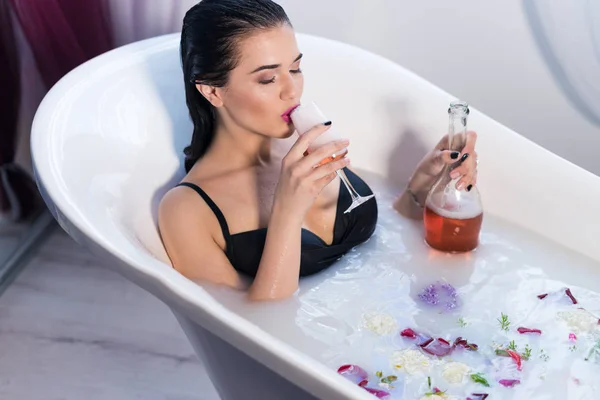 Sexy brunette woman taking a hot bath with flowers — Stock Photo, Image