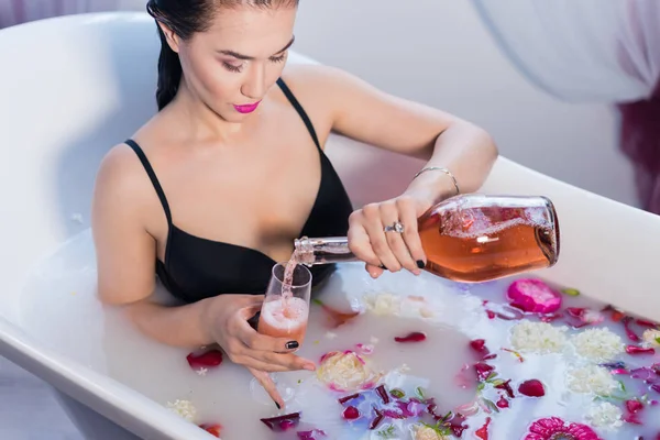 Sexy brunette woman pouring champagne in bath — Stock Photo, Image
