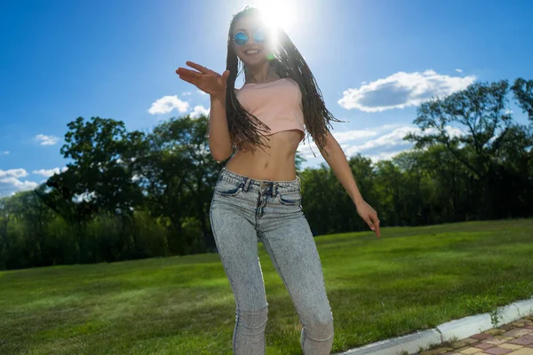 Chica despreocupada con zizi cornrows rastas bailando sobre césped verde —  Fotos de Stock