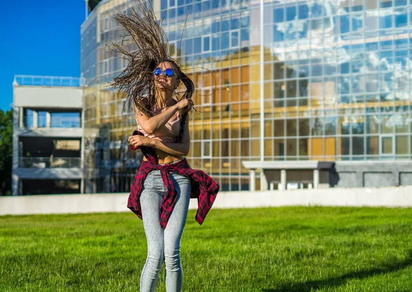 Carefree girl with zizi cornrows dreadlocks dancing on green lawn — Stock Photo, Image