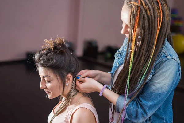 Волосся стиліст плете Зізі cornrows до молодою і красивою дівчиною — стокове фото