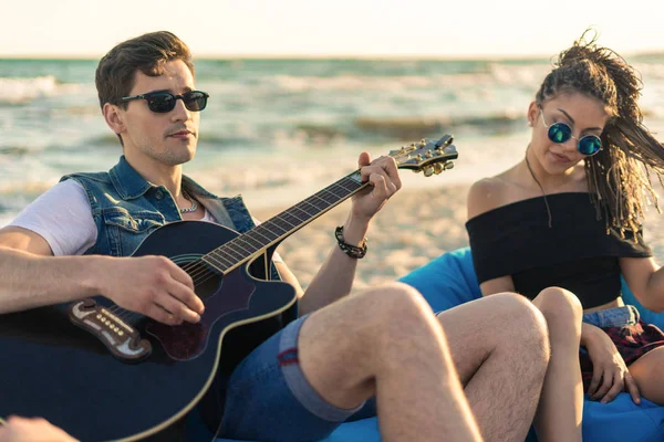 Guitarra divertida. Guapo joven hipster hombre tocando la guitarra en la playa — Foto de Stock