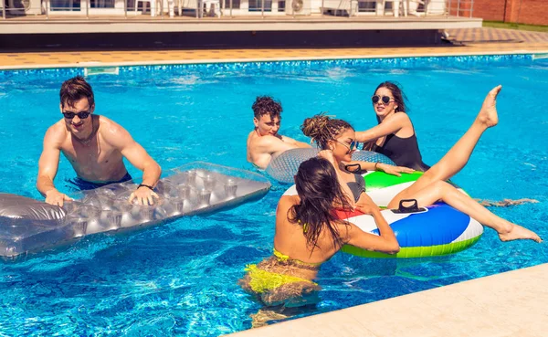 Чоловіки і жінки грають у басейні з плавальними колами — стокове фото