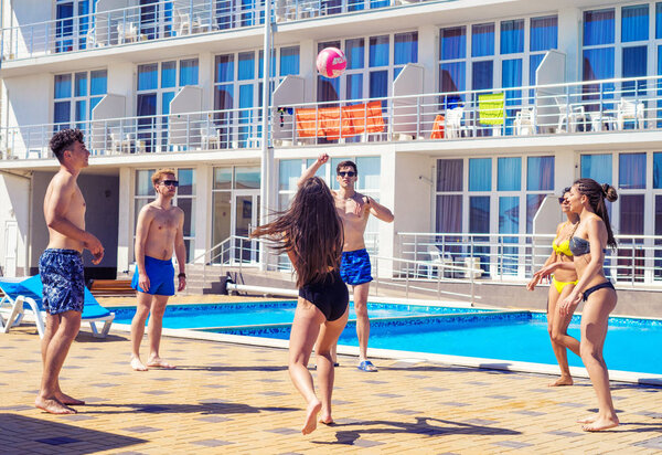 Group of cheerful couples friends playing volleyball