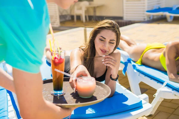 Camarero trae coloridos cócteles a la joven chica sexy para una fiesta en la piscina — Foto de Stock