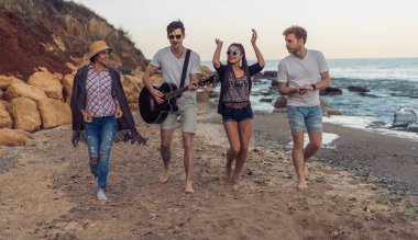 Kumsalda yürüyen genç ve neşeli arkadaş grubu