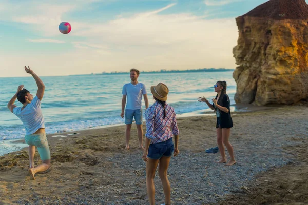 Freunde spielen bei Sonnenuntergang an einem wilden Strand Volleyball — Stockfoto