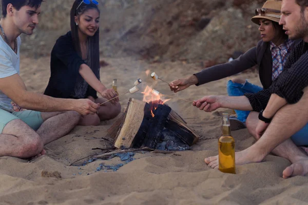 Amici su una spiaggia selvaggia acceso un falò e friggere marshmallows — Foto Stock