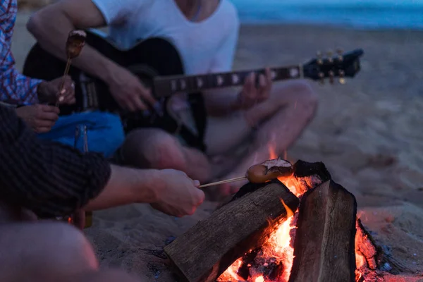 Freunde sitzen am Strand. Mann spielt Gitarre. — Stockfoto