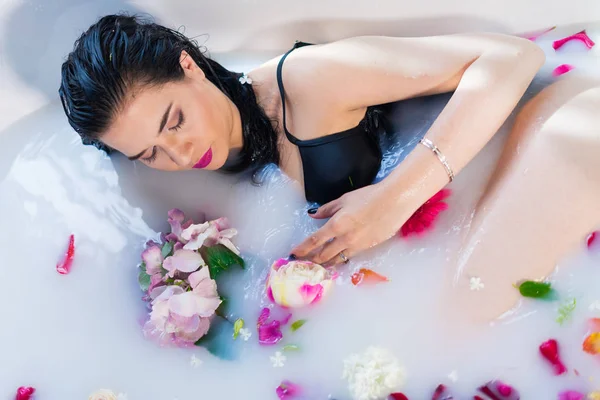 Sexy donna bruna rilassante in un bagno caldo con fiori — Foto Stock