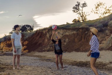 günbatımı sırasında vahşi bir sahilde voleybol oynarken arkadaşlar