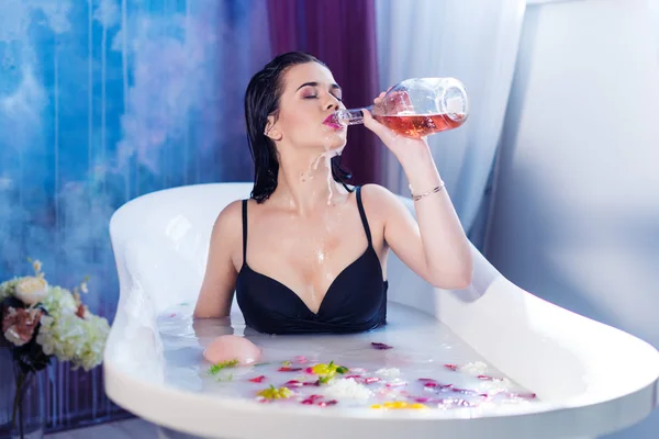 Sexy brunette woman drinking champagne while taking hot bath — Stock Photo, Image