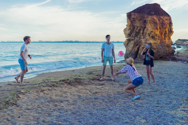 Freunde spielen bei Sonnenuntergang an einem wilden Strand Volleyball — Stockfoto