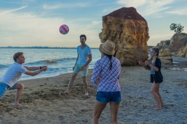 在日落期间野生的沙滩上打排球的朋友 — 图库照片