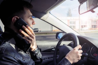 Genç adam bir araba sürüş sırasında cep telefonu konuşma