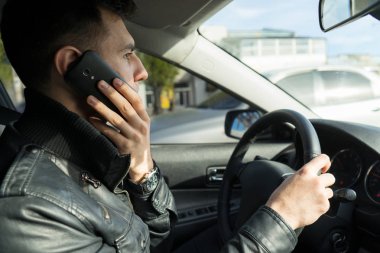 Genç adam bir araba sürüş sırasında cep telefonu konuşma