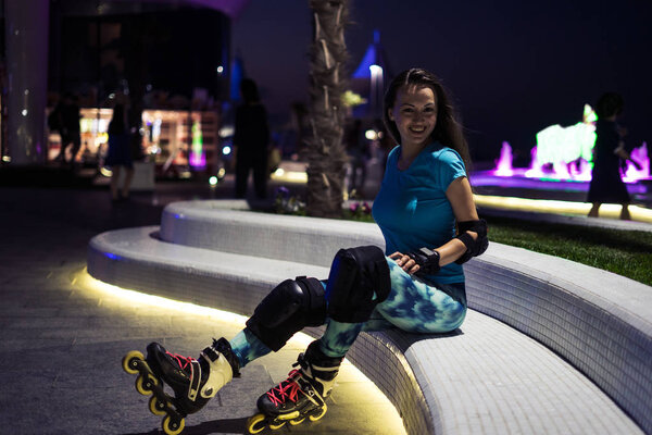 caucasian girl enjoys roller skating at night city with lights in bokeh