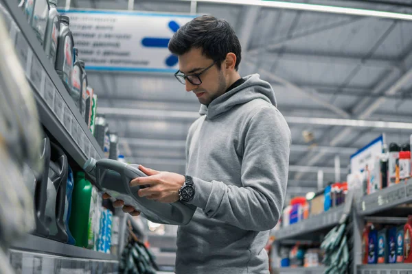 Cliente masculino que compra aceite lubricante del motor en el supermercado del coche — Foto de Stock